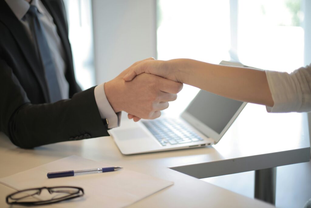 pexels-photo-3760069-3760069 Close-up of a professional handshake over a laptop during a business meeting in an office.